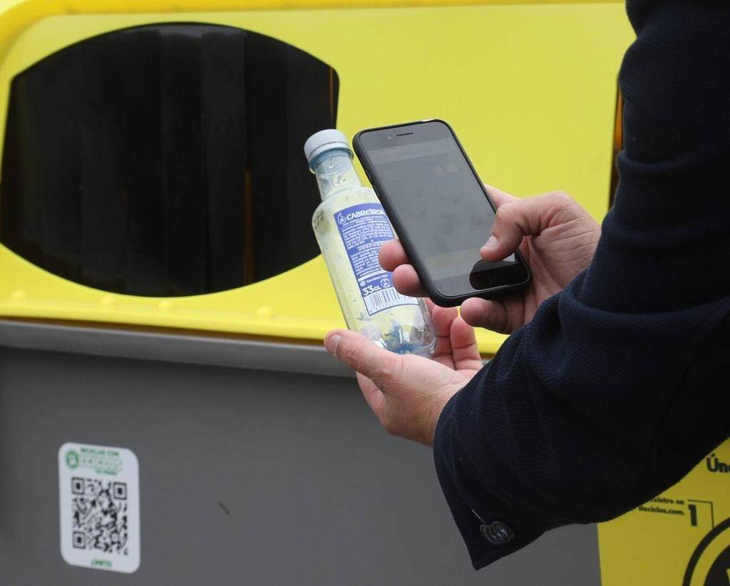 Un usuario hace una foto al código de barras antes de reciclar una botella.
